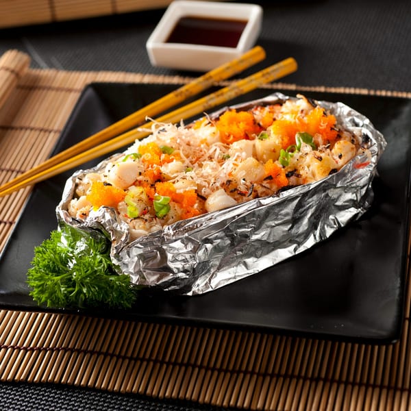 Baked scallops and rice in foil, topped with orange roe, green onions, and bonito flakes.