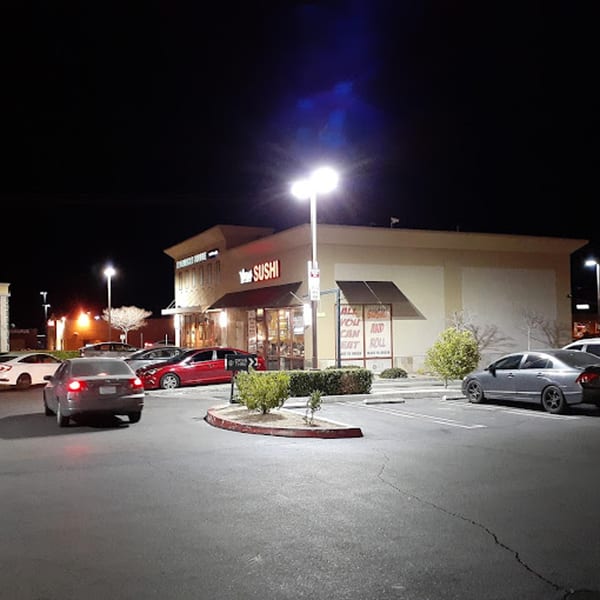 Exterior of Yoshi Japanese Cuisine at night, with cars parked in the illuminated lot.
