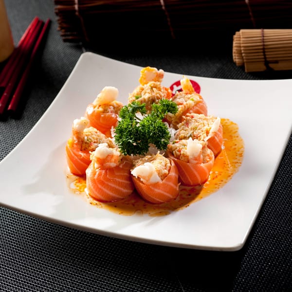 Yoshi Japanese Cuisine's salmon sushi rolls with crab and shrimp, garnished with parsley on a white plate.